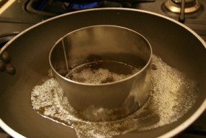 A plating ring in a pan of butter.